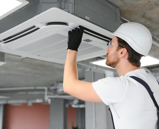 happy male technician repairing air conditioner